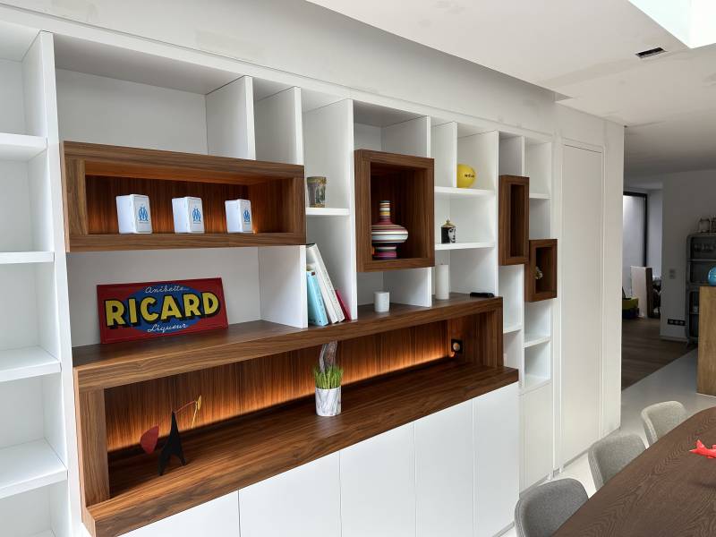 Conception d'une bibliothèque intégrée sur mesure en medium laqué blanc et niches en noyer massif pour une villa à La Ciotat