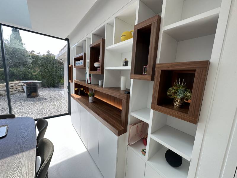 Conception d'une bibliothèque intégrée sur mesure en medium laqué blanc et niches en noyer massif pour une villa à La Ciotat