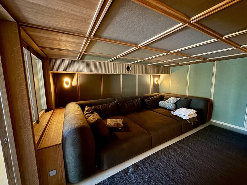 Conception sur mesure d’une salle de cinéma privée en chêne verni et tissu acoustique en Corse